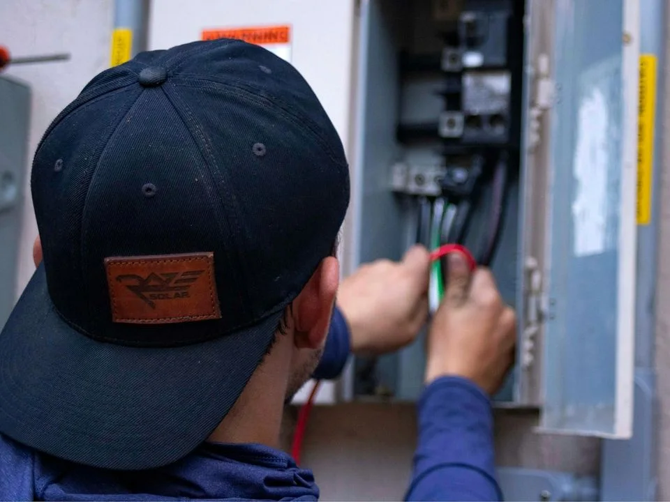 Eletricista com as mãos dentro de um quadro elétrico aberto, fazendo manutenção
